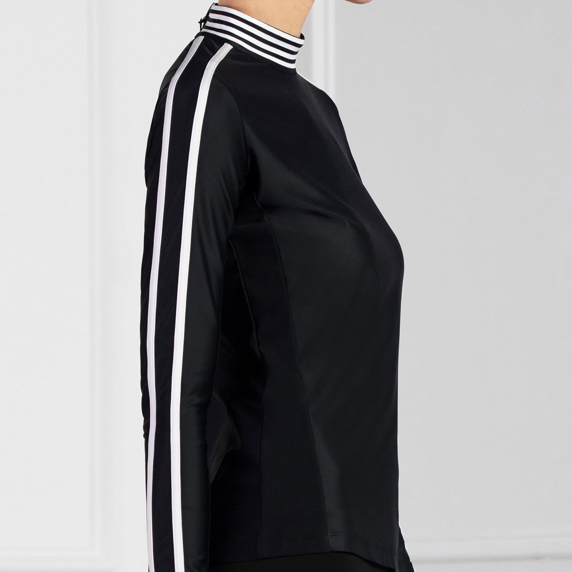Angled side view of model in PXG Mock Neck Ladies Long Sleeve Golf Polo Shirt black